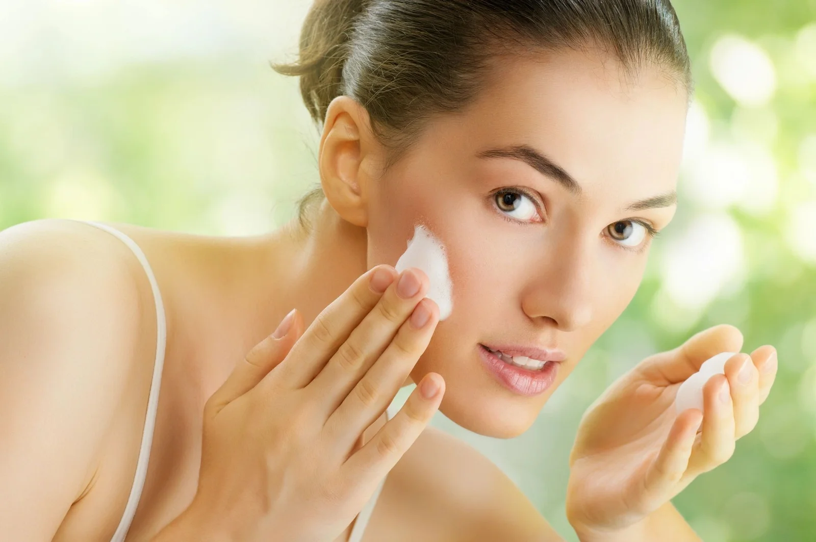 Woman applying cream to her cheek