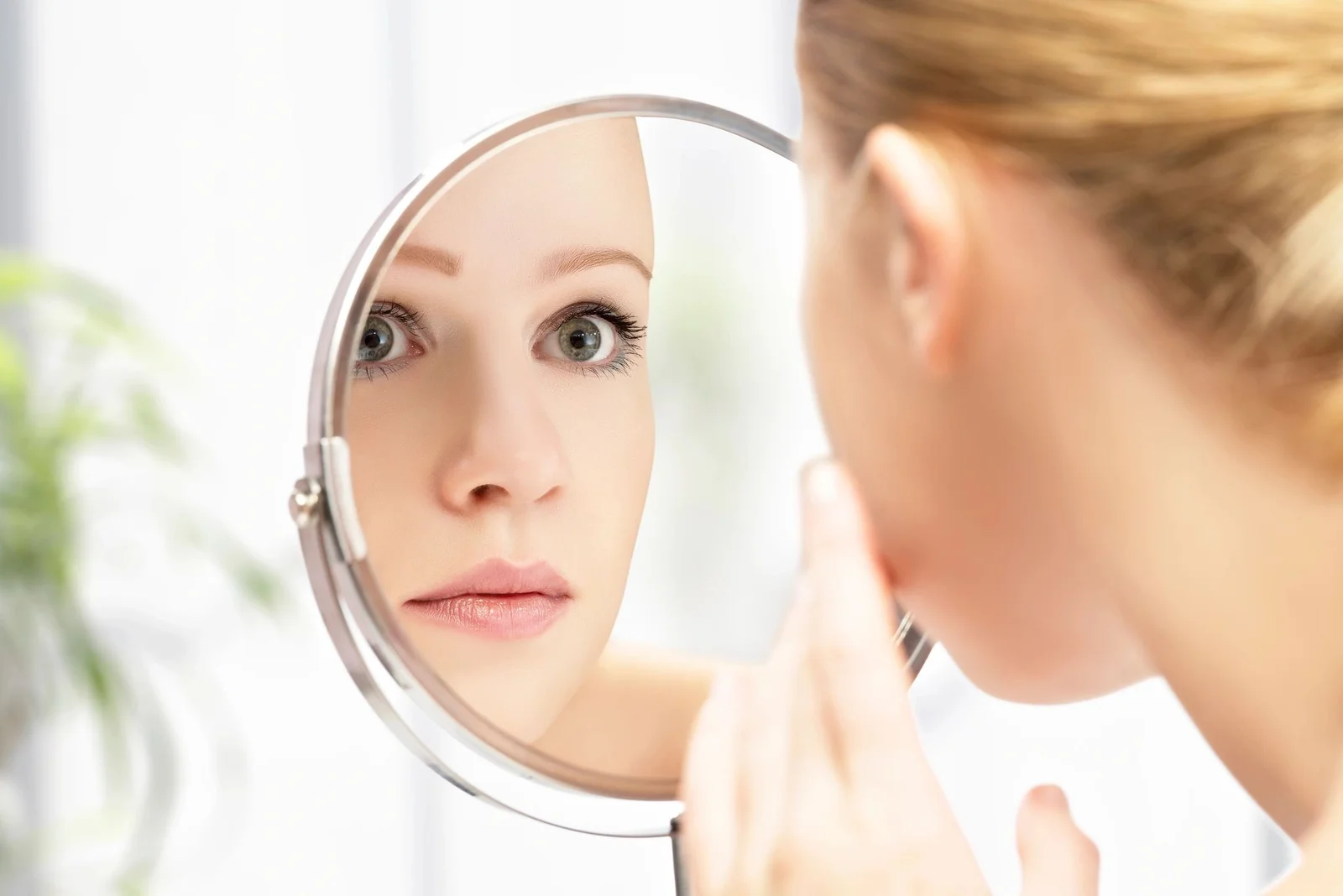 Woman looking at her face in a mirror