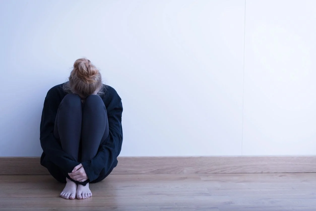 Woman sitting with her head resting on her knees