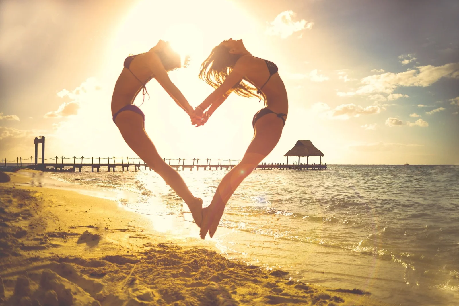 Hands forming a heart shape in front of the sunset